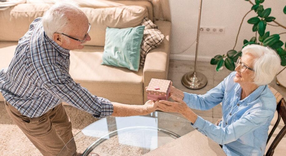 Elderly couple exchanging a small gift box.