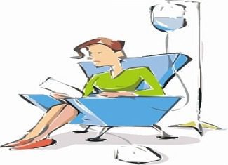 Woman sitting, receiving intravenous therapy, reading paper.
