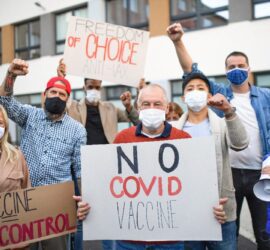 Protesters holding anti-vaccine signs and banners.