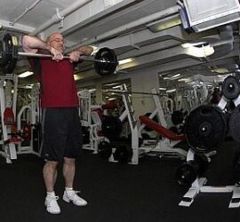 Man lifting barbell in a gym.