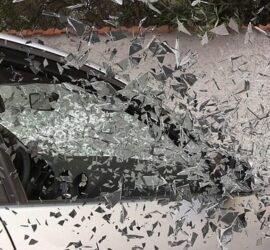 Shattered car window with flying glass fragments.