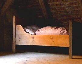 Wooden bed in a rustic attic room.