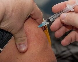 Arm receiving a vaccine injection with syringe.
