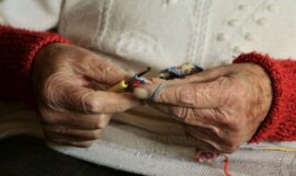 Elderly hands knitting with colorful yarn.