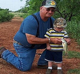 Man and child holding a fish outdoors.