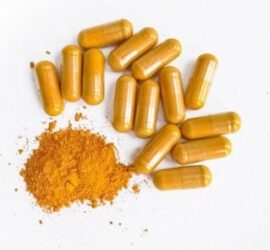 Yellow capsules and powder on white background.