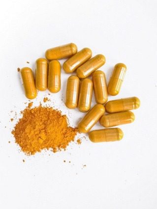 Yellow capsules and powder on white background.