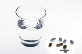 Glass of water and scattered pills.