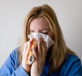 Person blowing their nose with a tissue.